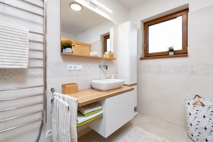 Moderní světlá koupelna s dřevěnými prvky a bílým umyvadlem